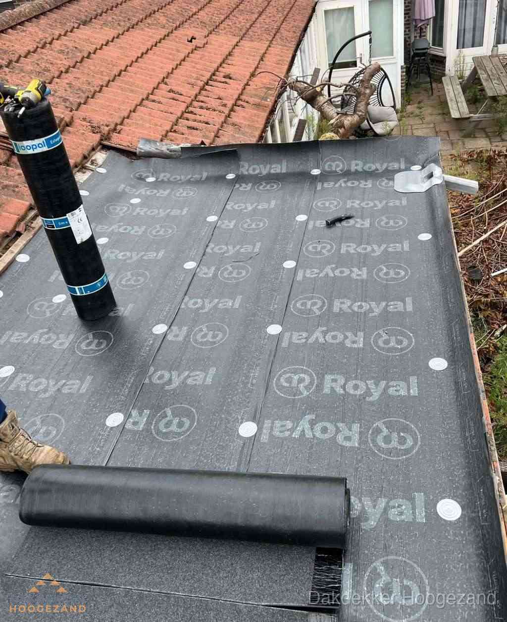 Plat dak met nieuwe bitumen dakbedekking en brandgereedschap in Hoogezand