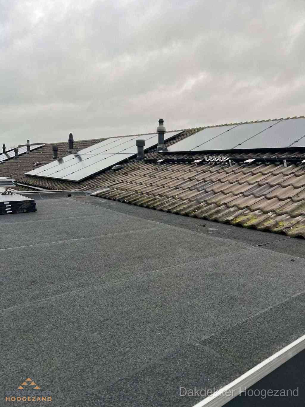 Plat dak inspectie met bitumen bedekking naast schuin pannendak in Hoogezand