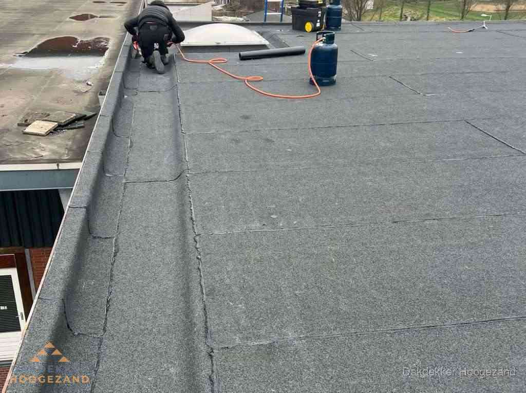 Dakdekker repareert bitumen dakbedekking op groot plat dak in Hoogezand