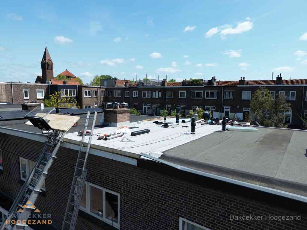 Dakdekkers aan het werk op plat dak in Hoogezand