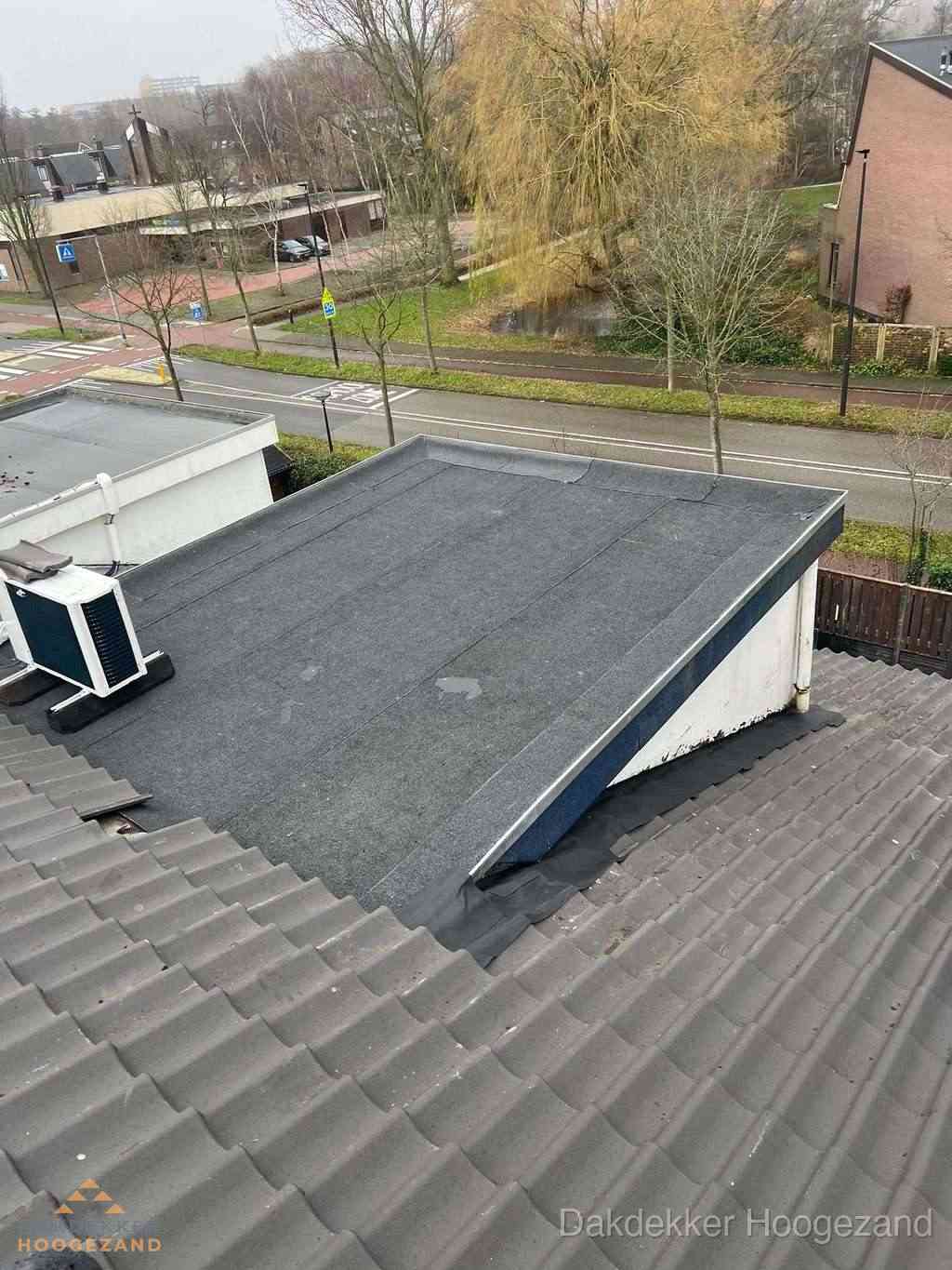 Plat dak met bitumen dakbedekking naast schuin pannendak in Hoogezand
